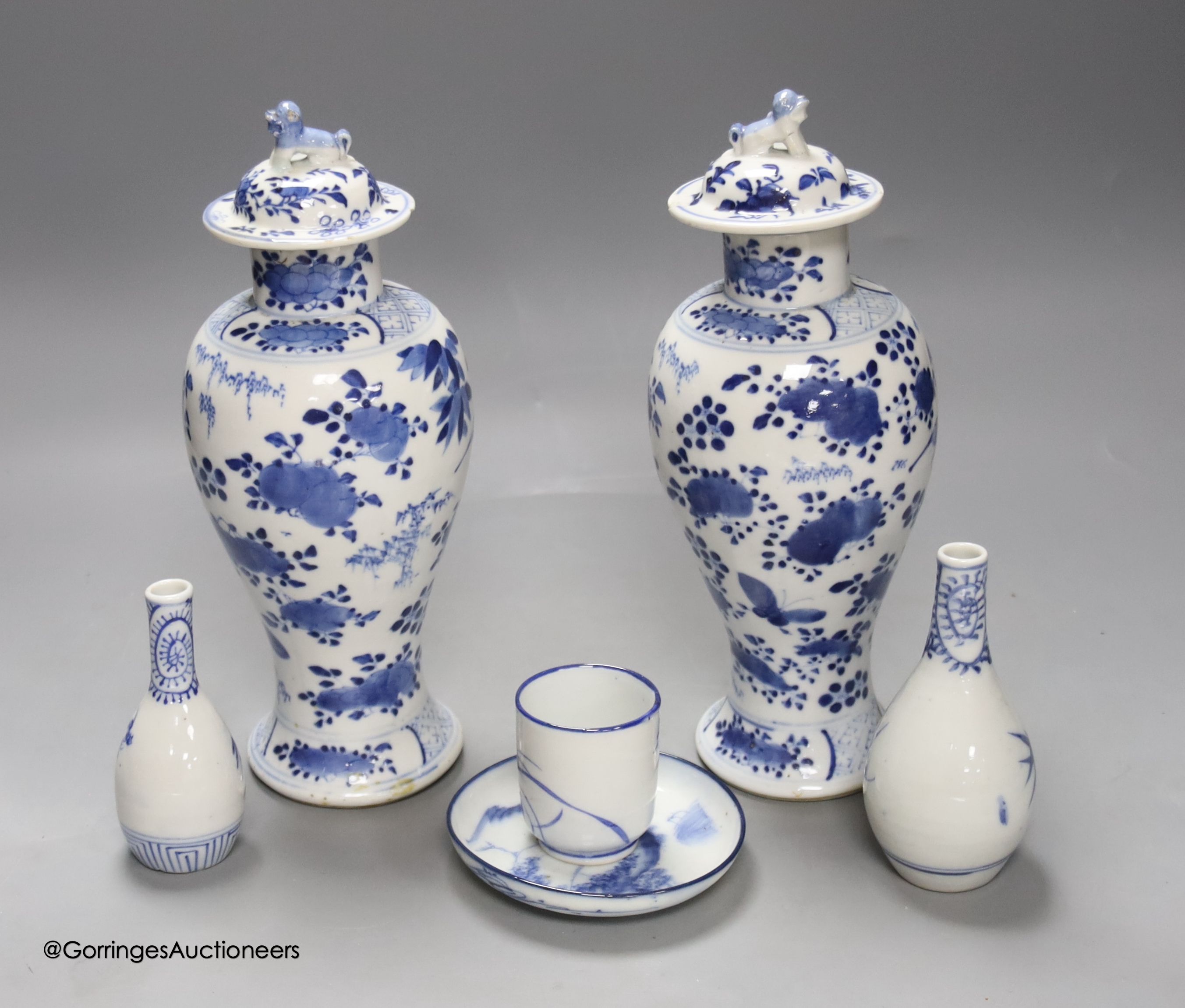 A pair of lidded Chinese blue and white vases, c.1900, Kangxi marks, 23cm high, together with two small Japanese vases, and a cup and saucer (6)